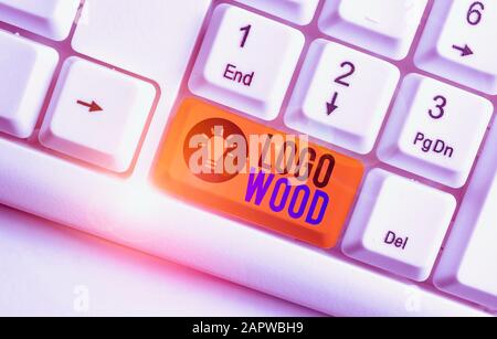 Handschrift text Logo Holz. Konzeptionelle Foto erkennbaren Design oder das Symbol eines Unternehmens eingeschrieben auf Holz weiß PC-Tastatur mit leeren Papier abov Stockfoto