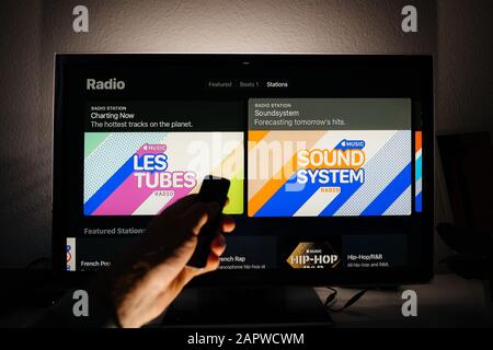 Paris, Frankreich - Ca. 2019: Verwenden der Fernbedienung im Apple TV-Menü im Panasonic Plasma tv Wohnzimmer mit Top 100 Listen-Charts Charting Now und Radiosender Forecasting Tomorrow Hits Playlist von Apple Music Stockfoto