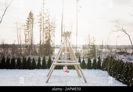 Schneebedeckter Kinderkletterrahmen und Schaukel in einem Garten zu Hause Stockfoto