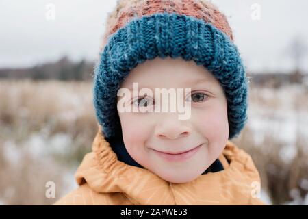 Porträt eines jungen Jungen lächelnd beim Spielen draußen im Winter Stockfoto