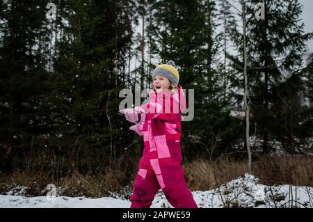 Mädchen spielt im Schnee lachend werfen einen Schneeball Stockfoto