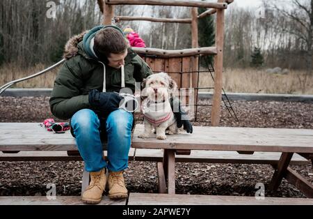 Der Mann saß mit seinem Hund draußen auf einer Parkbank Stockfoto