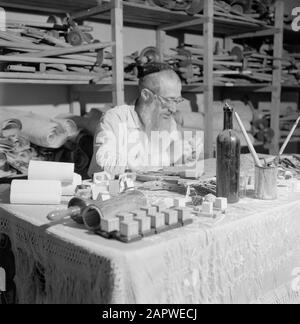 Israel 1964-1965: Jerusalem (Jerusalem), Thorarrolls Man macht thora Rollen hinter einem vollen Arbeitstisch Anmerkung: Die Tora (das Mosaische Gesetz) ist auf einer Rolle geschrieben, die von der Haut eines koscheren Tieres aus Pergament gefertigt wurde. Die verschiedenen Teile von Pergament sind mit einer Sehne aneinander befestigt, der Text wird handschriftlich geschrieben. Die Tinte wird oft von selbst hergestellt und muss bestimmte Anforderungen erfüllen. Schließlich ist die Rolle an zwei Holzstöcken mit Griffen befestigt und beide Enden werden gegen das mittlere Datum gerollt: 1964 Ort: Israel, Jerusalem Schlüsselwörter: Thorarol, Werkzeuge, Handarbeit, jüdische Religion Stockfoto