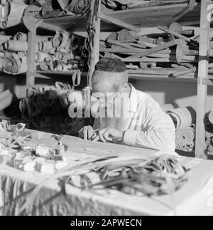 Israel 1964-1965: Jerusalem (Jerusalem), Thorarrolls Man macht thora Rollen hinter einem vollen Arbeitstisch Anmerkung: Die Tora (das Mosaische Gesetz) ist auf einer Rolle geschrieben, die von der Haut eines koscheren Tieres aus Pergament gefertigt wurde. Die verschiedenen Teile von Pergament sind mit einer Sehne aneinander befestigt, der Text wird handschriftlich geschrieben. Die Tinte wird oft von selbst hergestellt und muss bestimmte Anforderungen erfüllen. Schließlich ist die Rolle an zwei Holzstöcken mit Griffen befestigt und beide Enden werden gegen das mittlere Datum gerollt: 1964 Ort: Israel, Jerusalem Schlüsselwörter: Thorarol, Werkzeuge, Handarbeit, jüdische Religion Stockfoto