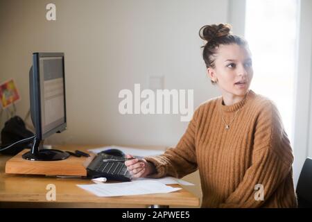 Junge Frau mit Brötchen im Büro Stockfoto