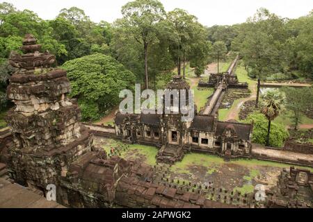 Wenige Touristen, die an einem regnerischen Morgen um den Baphuon-Tempel spazieren Stockfoto