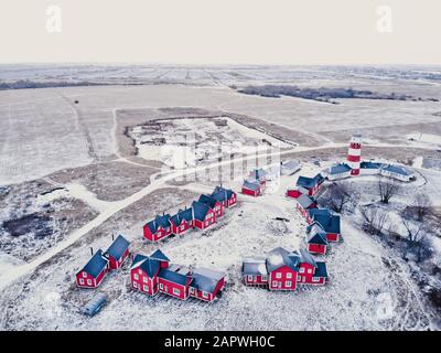 Rote Holzhäuser des Fischerdorfs in schneebedecktem Schnee im Winter. Stilvolles und modernes Fischerdorf aus Vogelperspektive. Ein paar rote Häuser in der Nähe des Stockfoto