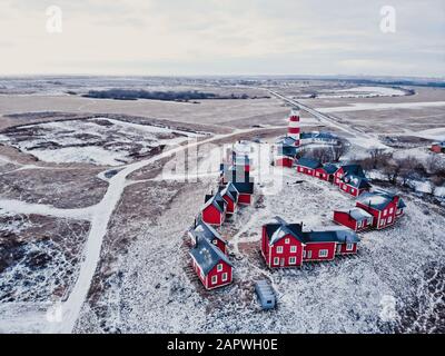 Rote Holzhäuser des Fischerdorfs in schneebedecktem Schnee im Winter. Stilvolles und modernes Fischerdorf aus Vogelperspektive. Ein paar rote Häuser in der Nähe des Stockfoto