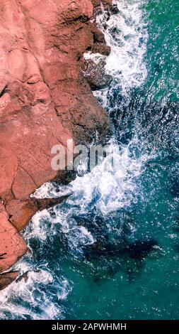 Luftaufnahme von Wellen, die am felsigen Strand in Kalifornien plätschern Stockfoto