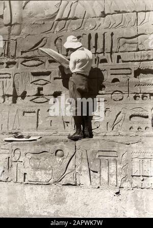 Ägyptische Zivilisation. Ein fleißiger Tourist, der anscheinend ein Gelehrter und Kenner des Keilschrifttextes ist, kopiert Zeichnungen und Schriften/Gliefen an den Wänden altägyptischer Denkmäler, Ägypten, im Jahre 1927. Stockfoto