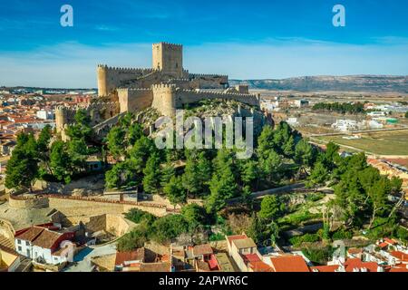 Luftaufnahme der mittelalterlichen Burg Almansa mit Donjon und Innenhof auf einem Felsen, der von dem von einem runden Ring aus roten Dachhäusern umgebenen Plateau auftaucht Stockfoto