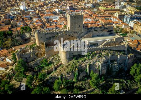 Luftaufnahme der mittelalterlichen Burg Almansa mit Donjon und Innenhof auf einem Felsen, der von dem von einem runden Ring aus roten Dachhäusern umgebenen Plateau auftaucht Stockfoto