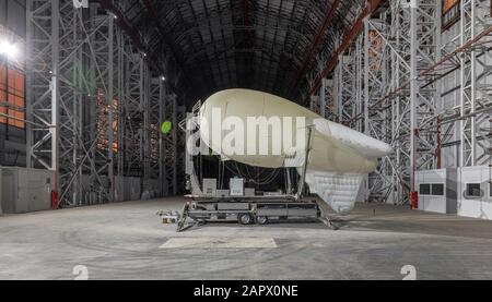 Kleine Blimp auf einer Anlegestelle in einem riesigen Luftschiffhangar. Seitenansicht Stockfoto