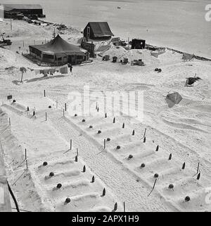Leere Helme und abgebrannte Artillerie-Granaten markieren die Gräber von Marines, die bei Tarawa fielen, März 1944. Gräber von US-Marines, die bei der Einnahme von Tarawa ums Leben kamen, bevor Kopfsteine vorbereitet wurden. Im Hintergrund stehen die ersten Zelte, die nach der Besetzung der Insel aufgestellt wurden. Stockfoto