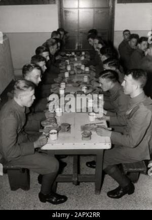 Niederländische Armee, Kolonialtruppen, KNIL. Militär serviert Mahlzeiten im Speisesaal der Kaserne des Colonial Reserve in Nijmegen. Auf dem Tisch Brotplatten mit dicken Brotsorten und Emailfresschen (Tassen) mit Alkohol. Niederlande, 1939. Stockfoto