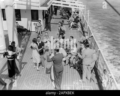 Seereise mit Frau Johan van Oldenbarnevelt nach Norwegen Schiffsorchester spielt an Deck: Passagiere, die bis zum Musikdatum tanzen: 1933 Ort: Norwegen Schlüsselwörter: Kreuzfahrten, Kreuzfahrtschiffe, Tänzer, Dirigenten, Gitarren, Musikinstrumente, Orchester, Passagierschiffe, Publikum, Reisende, Saxophone, Streichinstrumente, Tourismus, Schlagzeug Stockfoto