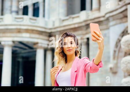 Außenporträt einer jungen Frau, die ein selfie vor einem Wahrzeichen von Mexiko-Stadt nimmt. Blick auf die Kamera Stockfoto