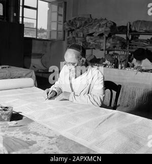 Israel 1964-1965: Jerusalem (Jerusalem), Thorarrolls Torah Writer at Work hinter einem Arbeitstisch Anmerkung: Die Tora (das Mosaische Gesetz) ist auf einer Rolle geschrieben, die aus Pergament von der Haut eines koscheren Tieres besteht. Die verschiedenen Teile von Pergament sind mit einer Sehne aneinander befestigt, der Text wird handschriftlich geschrieben. Die Tinte wird oft von selbst hergestellt und muss bestimmte Anforderungen erfüllen. Schließlich ist die Rolle an zwei Holzstöcken mit Griffen befestigt und beide Enden werden gegen das mittlere Datum gerollt: 1964 Ort: Israel, Jerusalem Schlüsselwörter: Tora, Handschrift, jüdische Religion, Schriftsteller, Arbeit Stockfoto