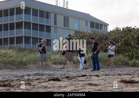 Eine Gruppe junger Leute scannt diesen Strand auf Hutchinson Island, Florida mit ihren Metalldetektoren auf der Suche nach einem verschütteten Schatz. Stockfoto