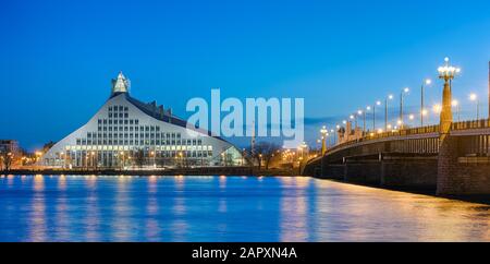 Brücke über den Fluss Duena mit Nationalbibliothek in der Abenddämmerung, Riga, Lettland Stockfoto