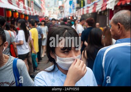 24.01.2020, Singapur, Republik Singapur, Asien - EINE Frau bedeckt ihr Gesicht mit einer chirurgischen Maske auf einem Straßenbasar in Chinatown. Stockfoto