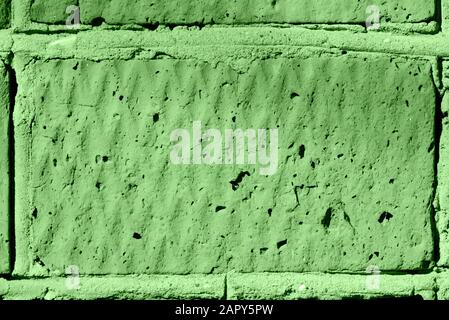 Die Struktur der Ziegelwand wird von der Sonne beleuchtet. Abstrakter Hintergrund, grüne Farbe Stockfoto