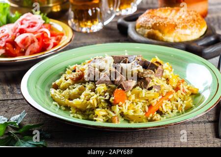 Nationale traditioneller Usbekischer Pilaw mit Fleisch und Reis auf einen hölzernen Tisch. Orientalische Küche Konzept. Nahaufnahme Stockfoto