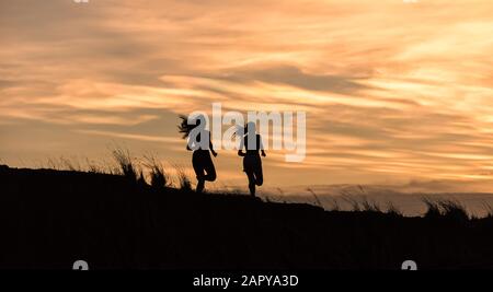 Junge Fitnessfrau, die bei Sonnenaufgang läuft Stockfoto