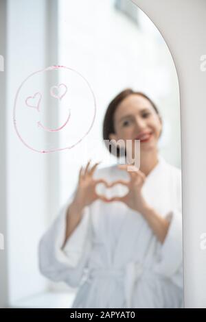 Amouröses Gesicht mit Lächeln und herzförmigen Augen und Spiegelung der jungen Frau Stockfoto