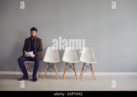 Der Arbeiter erwartet ein Interview, das auf einem Stuhl im Raum sitzt. Stockfoto