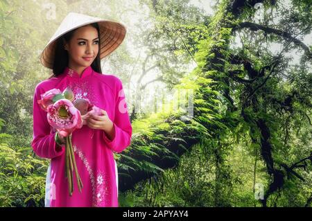 Porträt einer lächelnden jungen Frau mit langen Haaren, die ein traditionelles Kleid aus Vietnam trägt Stockfoto