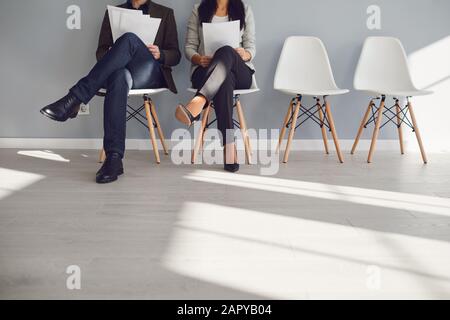 Zwei nicht erkennbare Geschäftsleute warten auf ein Interview, das auf einem Stuhl sitzt. Stockfoto