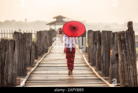 Burmesischen Frau mit traditionellen roten Schirm und Fuß auf U-Bein Brücke Stockfoto