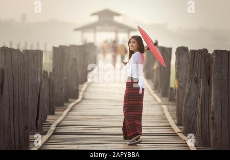 Burmesischen Frau mit traditionellen roten Schirm und Fuß auf U-Bein Brücke, Myanmar Stockfoto