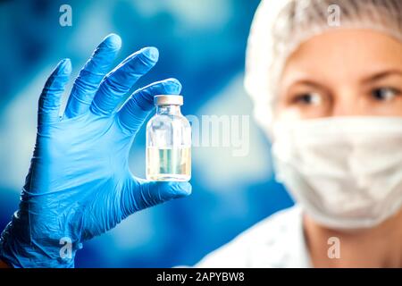 Ein Arzt in blauen Handschuhen, der eine Flasche mit Impfstoff hält. Nahaufnahme. Medizin- und Gesundheitskonzept, EIN Arzt in blauen Handschuhen, der eine Flasche mit V hält Stockfoto