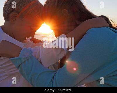 Bruder und eine Schwester stehen Kopf an Kopf mit dem Helle Sonne scheint n den Hintergrund Stockfoto