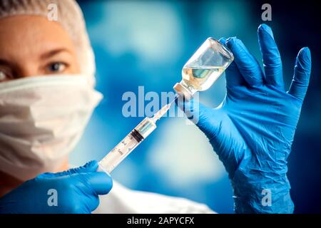 Arzt in medizinischen Handschuhen, der vor der Injektion eine Flasche mit Impfstoff und Spritze hält. Nahaufnahme. Medizin- und Gesundheitskonzept Stockfoto