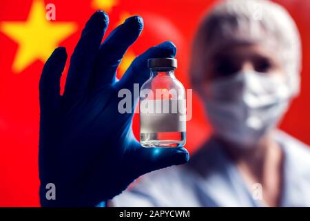 Ein Arzt in blauen medizinischen Handschuhen, der eine Flasche mit Impfstoff vor der Flagge Chinas hält. Nahaufnahme. Coronavirus, Epidemie und Gesundheitskonzept Stockfoto