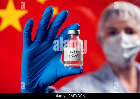 Ein Arzt in blauen medizinischen Handschuhen, der eine Flasche mit Impfstoff vor der Flagge Chinas hält. Nahaufnahme. Coronavirus, Epidemie und Gesundheitskonzept Stockfoto