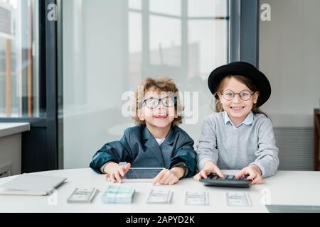 Zwei glückliche kleine Buchhalter mit Tablett und Taschenrechner, die Geld zählen Stockfoto