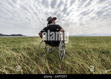 Mann auf einem Rollstuhl entspannend in einem park Stockfoto