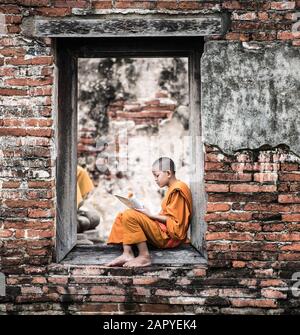 Südostasiatische Novizenmönche lesen Buch außerhalb des Klosters, buddhistische Lehre. Stockfoto