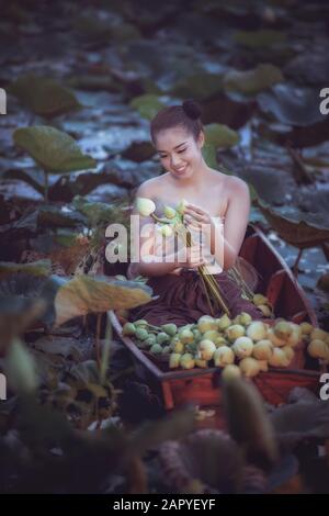 Schöne Frau im traditionellen thailändischen Anzug, die im Boot sitzt Stockfoto