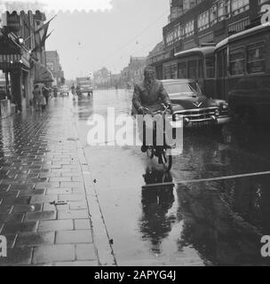 Gewitter über Amsterdam, Leute, die auf einem Fluchthügel warten, Mopedfahrer im Regen Datum: 19. August 1958 Ort: Amsterdam, Noord-Holland Schlüsselwörter: Mopeds, MENSCHEN, Regen: Lindeboom, Henk/Anefo Stockfoto