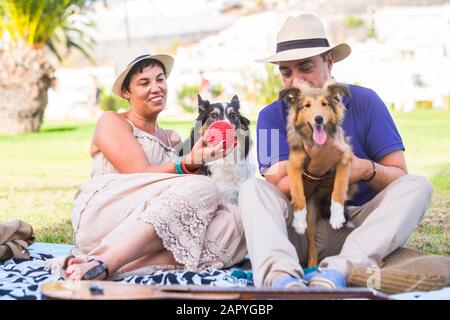 Freundschaft und Liebe zu Tieren Hundekonzept mit jungen kaukasischen Menschen im Park mit zwei lustigen Welpen, die eine schöne Freizeitaktivität haben Stockfoto