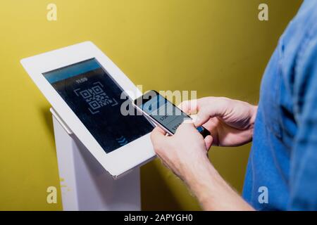 Hände junger zeitgenössischer Mann mit Smartphone am Terminal Stockfoto