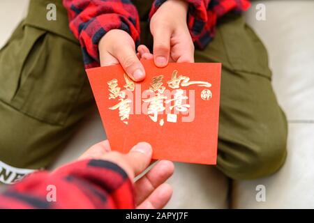 Der Vater, der der Übersetzung der chinesischen Schriftzeichen durch den Sohn rote Taschen schenkt, ist alles wie gewünscht Stockfoto