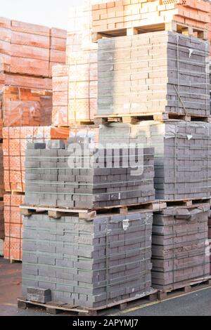 Mehrere Paletten mit Beton Ziegel übereinander im Depot gestapelt. Die industrielle Produktion von Backsteinen. vertikale Foto. Stockfoto