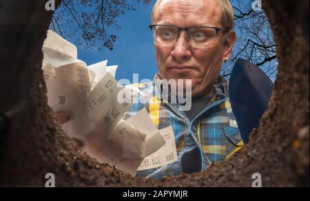 Ein Mann will seine Quittungen in einem Erdloch loswerden Stockfoto