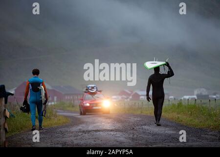 Zwei Surfer, die Surfbretter tragen und in der arktischen Nacht zum Strand laufen, Lofoten Islands, Nordland, Norwegen, Skandinavien Stockfoto